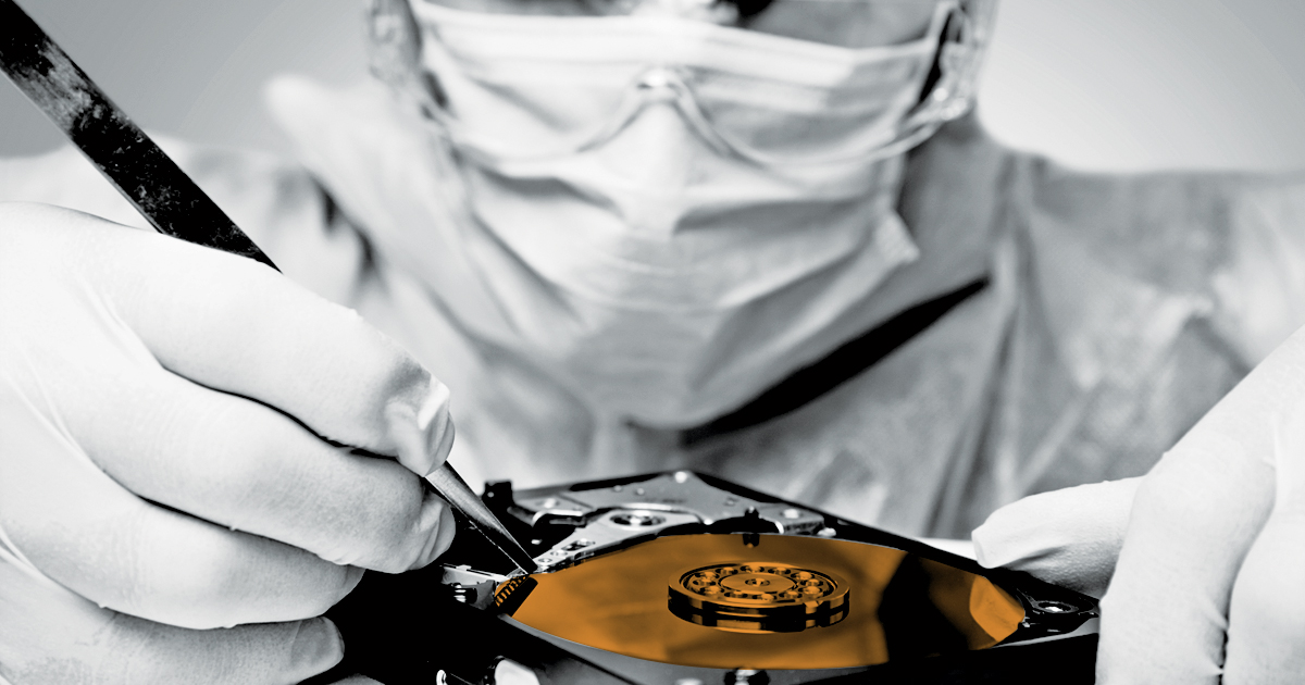 Image of a person in a mask examining a hard drive disk 