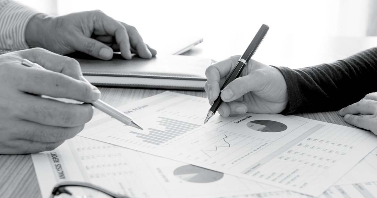 Image of Two people discussing s set of graphs in a tablet with one person pointing at a record with a pen