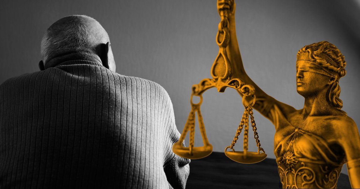 Image of a person sitting with their face in the hands, with a judge looking at them reading from a document infront of them.