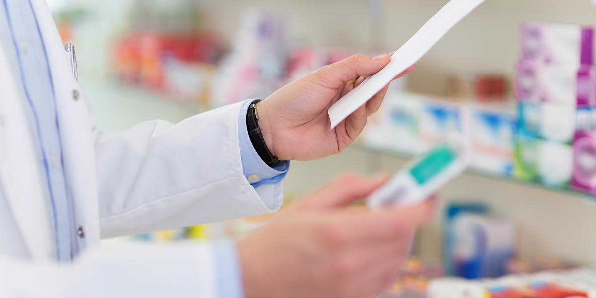 Pharmacist holding prescription form and prescription drugs in a pharmacy.