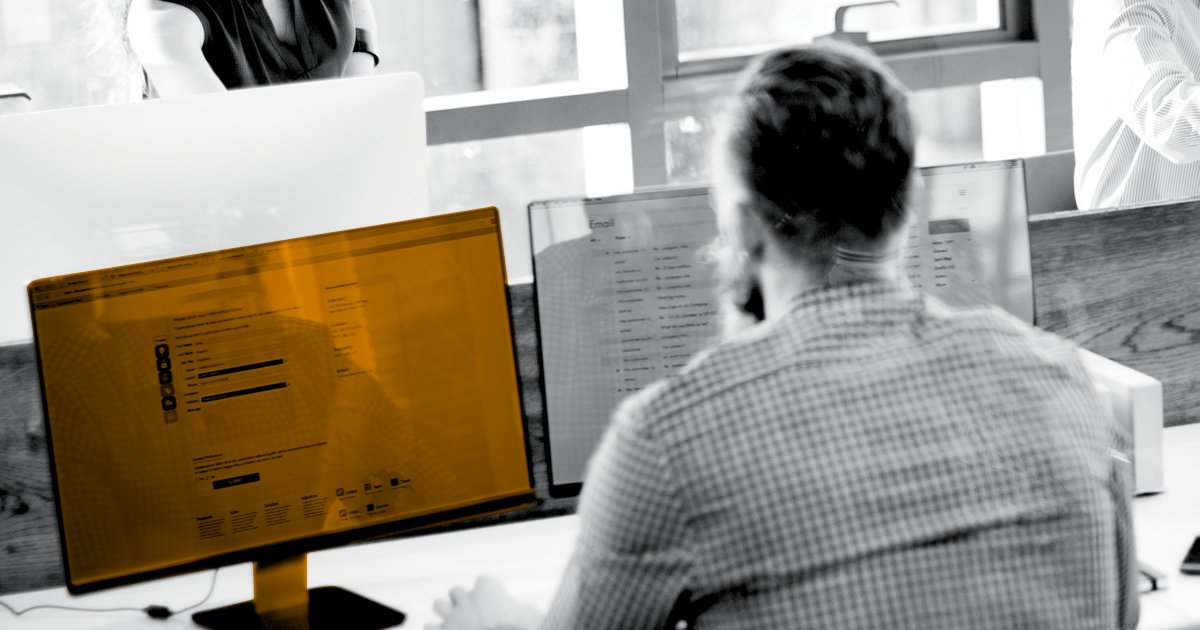 Image of a person sitting in front of a computer screen which is highlighted in orange